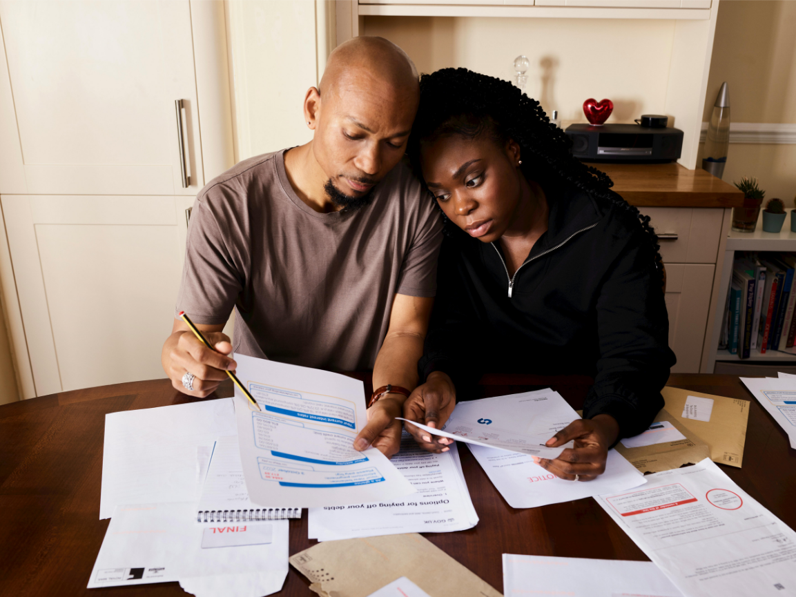 A couple sitting at their kitchen table going through unpaid accounts and letters together